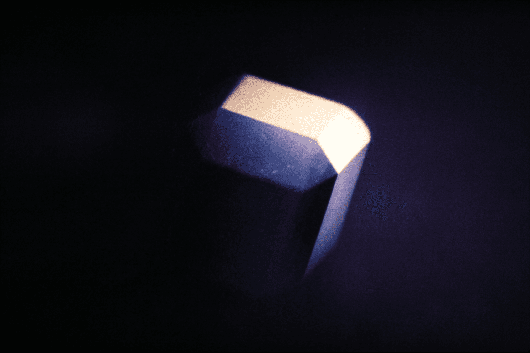 A softly lit crystal glowing against a dark background.